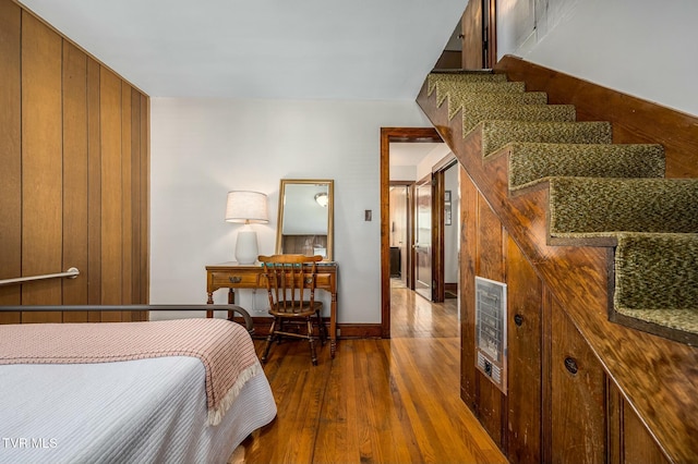 bedroom featuring hardwood / wood-style flooring, heating unit, and baseboards