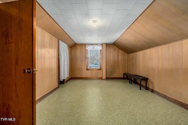 bonus room featuring lofted ceiling, wooden walls, and baseboards