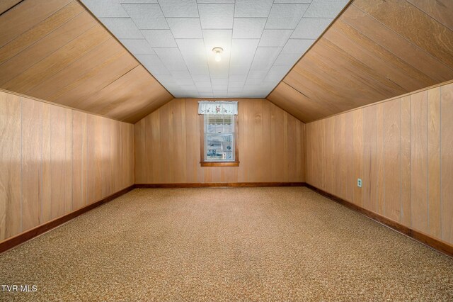 additional living space featuring baseboards, lofted ceiling, carpet floors, and wood walls