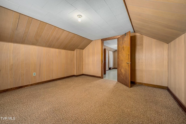 additional living space featuring baseboards, carpet, wood walls, and vaulted ceiling