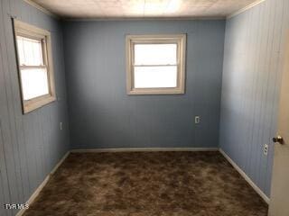 unfurnished room with dark colored carpet, baseboards, and ornamental molding