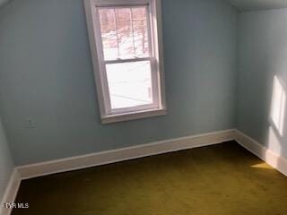 spare room featuring baseboards and vaulted ceiling