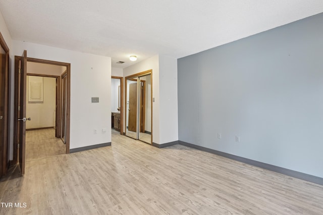 unfurnished bedroom with a closet, baseboards, and light wood-style floors