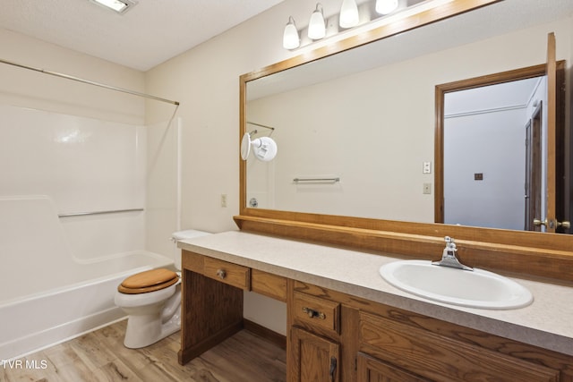 bathroom featuring toilet, shower / washtub combination, wood finished floors, and vanity