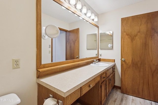 half bathroom with toilet, wood finished floors, and vanity