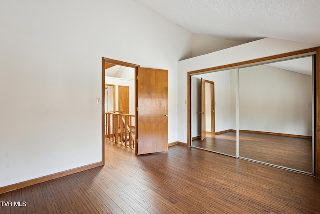 unfurnished bedroom with a closet, baseboards, dark wood finished floors, and vaulted ceiling