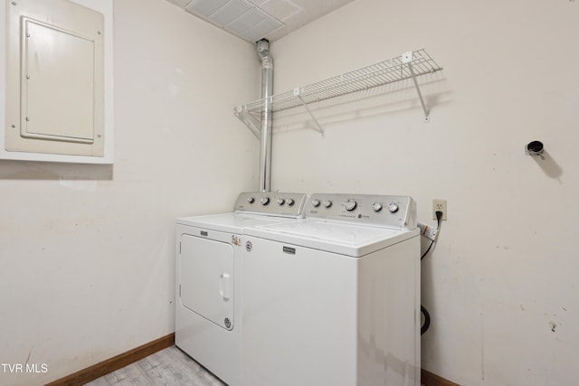 clothes washing area with baseboards, laundry area, light wood-style flooring, electric panel, and independent washer and dryer