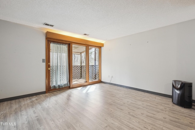 empty room with visible vents, baseboards, and light wood finished floors