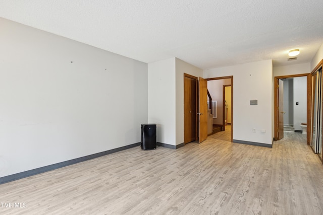 unfurnished room with visible vents, baseboards, light wood-style floors, and a textured ceiling