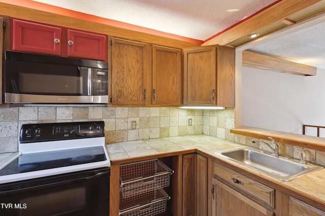 kitchen with decorative backsplash, range with electric stovetop, a textured ceiling, and a sink