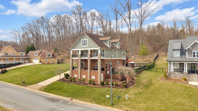 view of front of property featuring a balcony, fence, covered porch, a front lawn, and brick siding