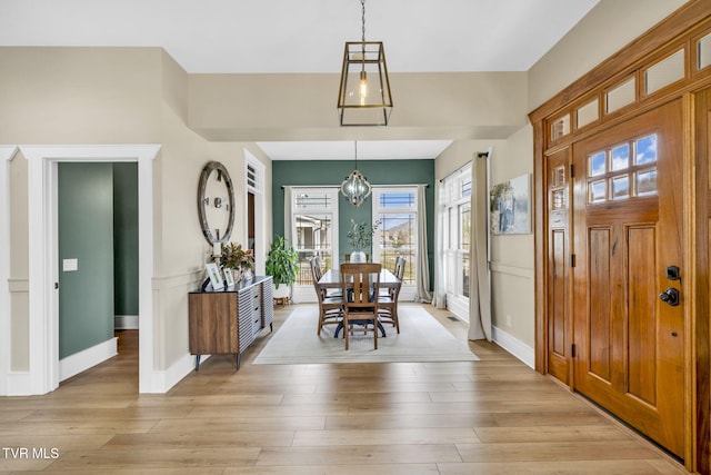 dining room with baseboards, a notable chandelier, and light wood finished floors