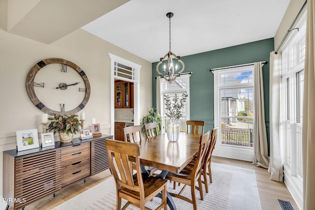 dining area featuring visible vents, a chandelier, and light wood finished floors