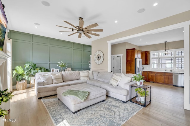 living room featuring a decorative wall, recessed lighting, light wood-style floors, and a ceiling fan