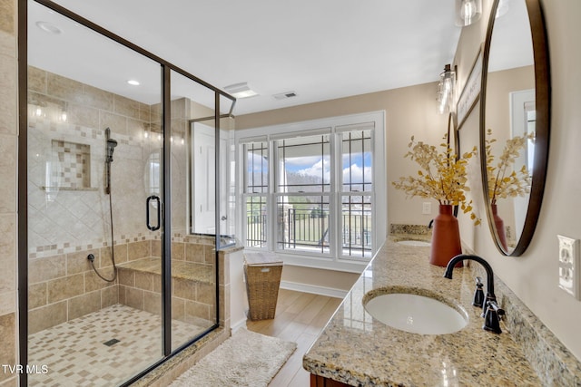 full bathroom featuring double vanity, visible vents, a shower stall, and a sink