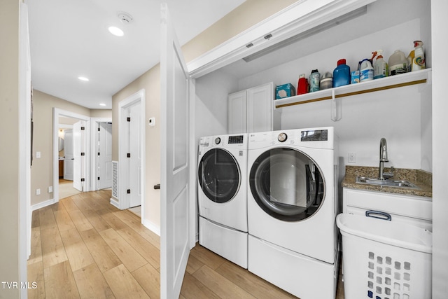 laundry room with light wood-type flooring, washer and clothes dryer, a sink, recessed lighting, and baseboards