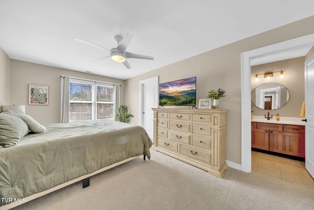 bedroom with light tile patterned floors, baseboards, ensuite bath, ceiling fan, and light carpet