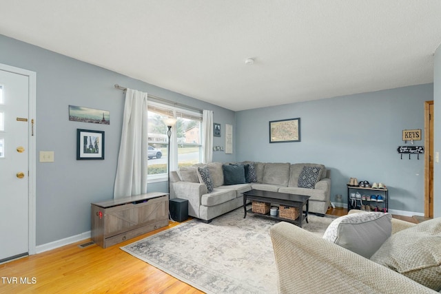 living room featuring visible vents, baseboards, and wood finished floors