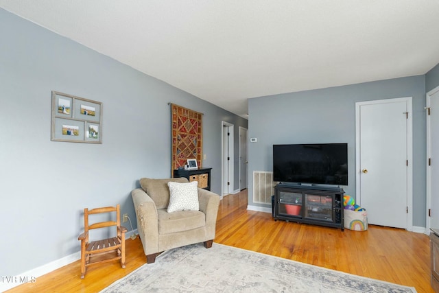 living area with visible vents, baseboards, and wood finished floors