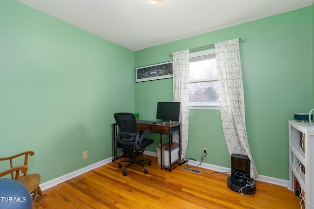 home office featuring visible vents, baseboards, and wood finished floors