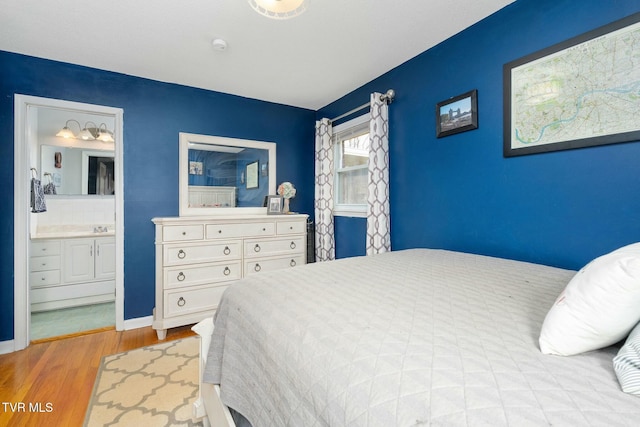 bedroom featuring ensuite bath, wood finished floors, and baseboards