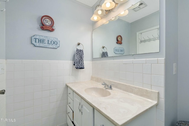 bathroom with vanity, tile walls, visible vents, and wainscoting