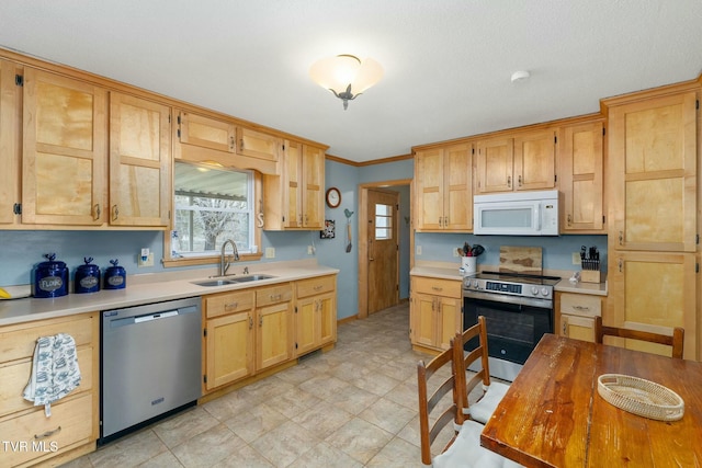 kitchen with a sink, appliances with stainless steel finishes, ornamental molding, and light countertops