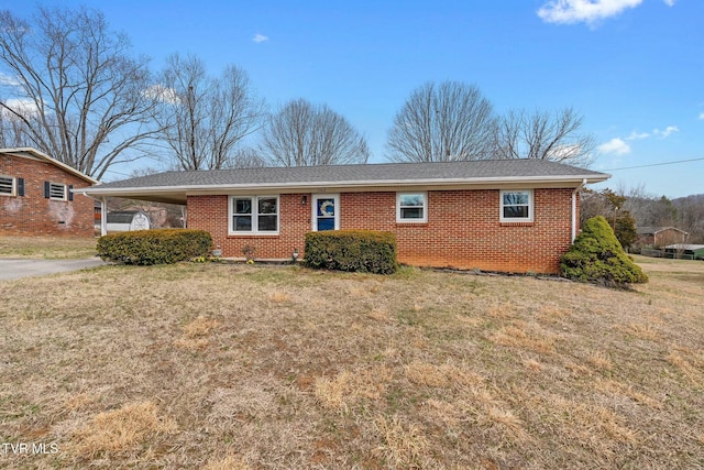 single story home featuring a front lawn, an attached carport, and brick siding