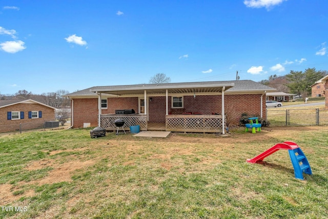 back of property with brick siding, a gate, fence, and a lawn