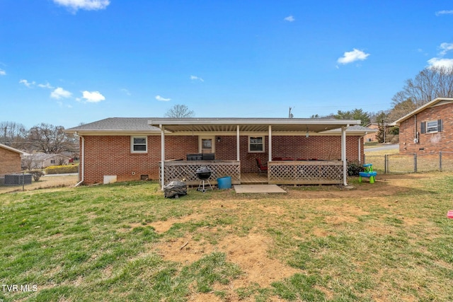 back of property with a yard, fence, brick siding, and crawl space