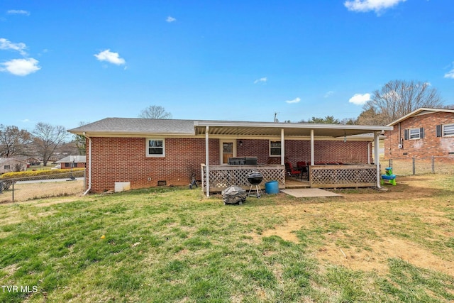 rear view of property with fence, brick siding, and a lawn