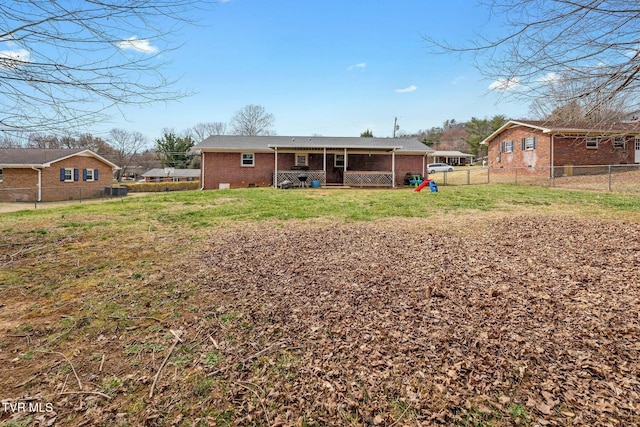 back of house with a yard, fence, and brick siding