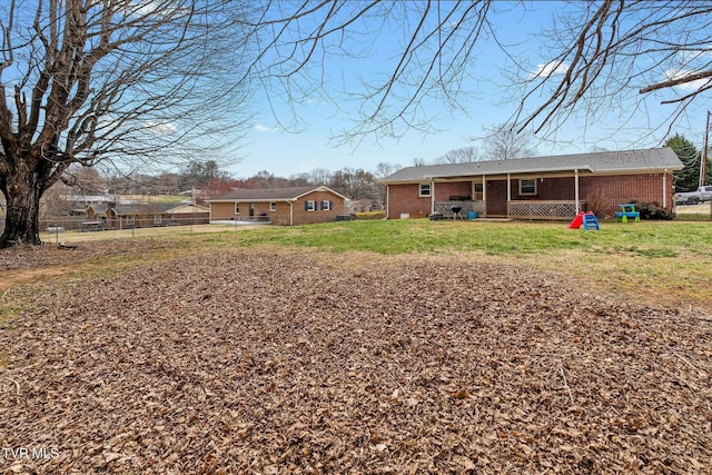 rear view of house with a yard, fence, and brick siding