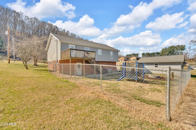 rear view of house with a deck, a yard, and fence