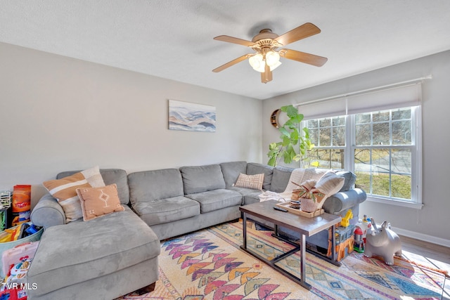 living room featuring baseboards, wood finished floors, and a ceiling fan