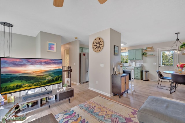 living area featuring baseboards, light wood-style floors, and ceiling fan