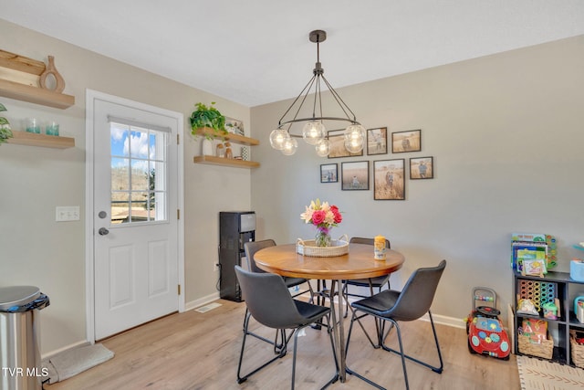 dining area with baseboards, light wood-style floors, and an inviting chandelier