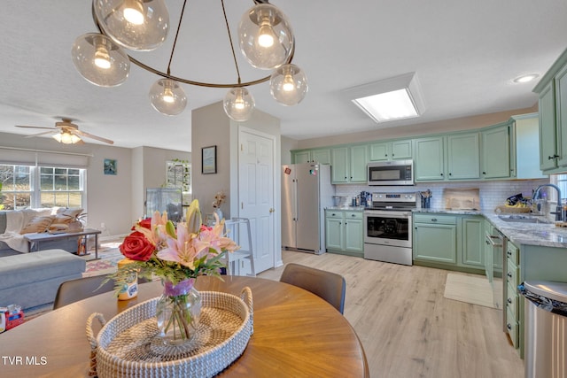 kitchen with a sink, tasteful backsplash, green cabinets, and stainless steel appliances