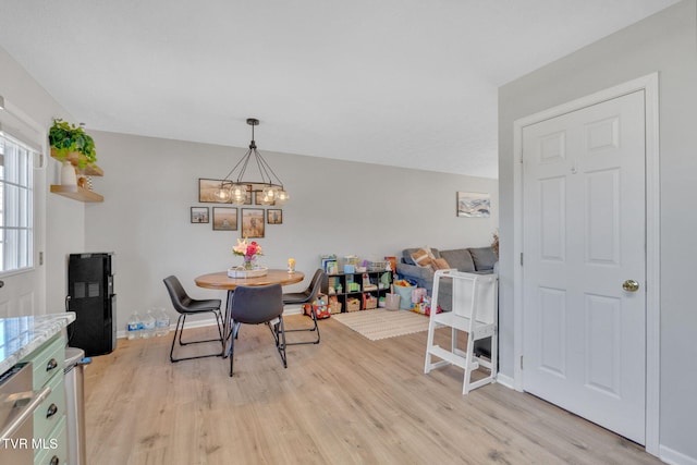 dining room with a chandelier, baseboards, and light wood-style flooring