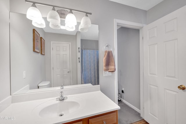 full bathroom with vanity, toilet, a notable chandelier, and baseboards