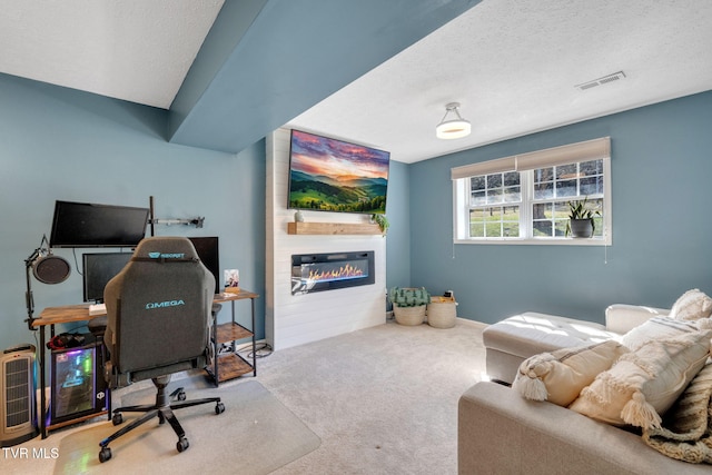 carpeted office featuring visible vents, a textured ceiling, and a large fireplace