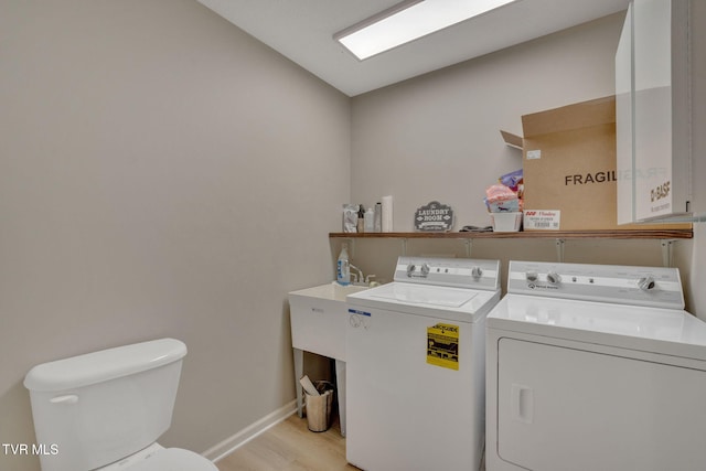 laundry room featuring light wood-type flooring, baseboards, and washing machine and clothes dryer