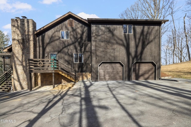 exterior space with stairway, a chimney, and a detached garage