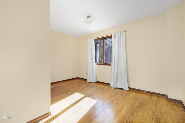 unfurnished room featuring light wood-style flooring, visible vents, and baseboards