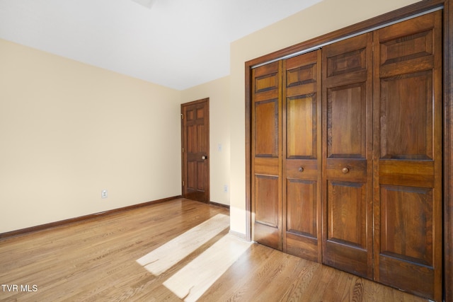 unfurnished bedroom featuring a closet, light wood-style flooring, and baseboards