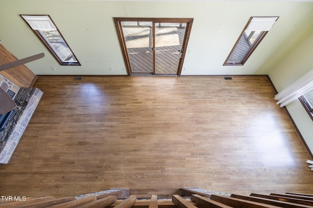 unfurnished living room featuring visible vents, wood finished floors, baseboards, and a skylight