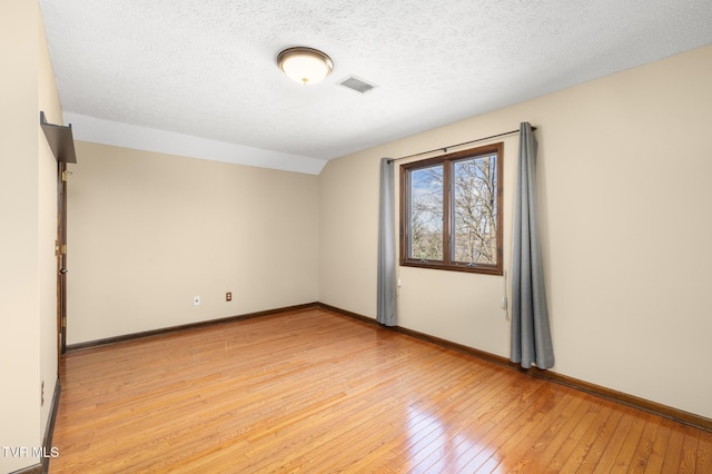 unfurnished room featuring light wood-type flooring, baseboards, a textured ceiling, and visible vents