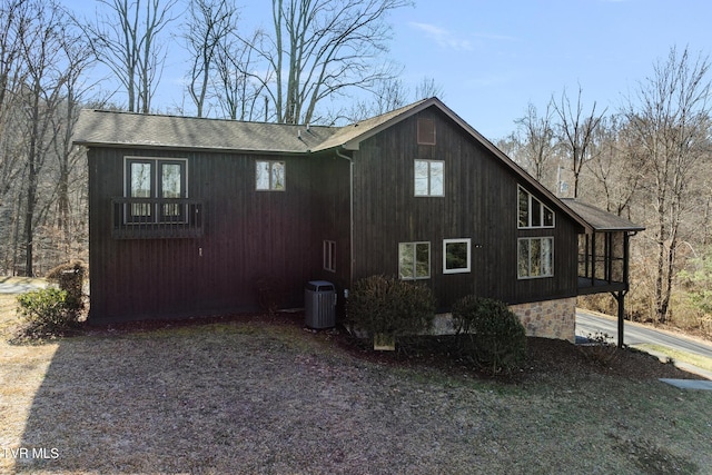 view of side of property with roof with shingles and central AC