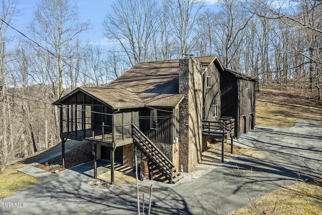 exterior space with aphalt driveway, stairway, and a sunroom