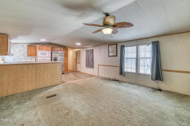 interior space featuring light carpet, visible vents, a textured ceiling, and vaulted ceiling